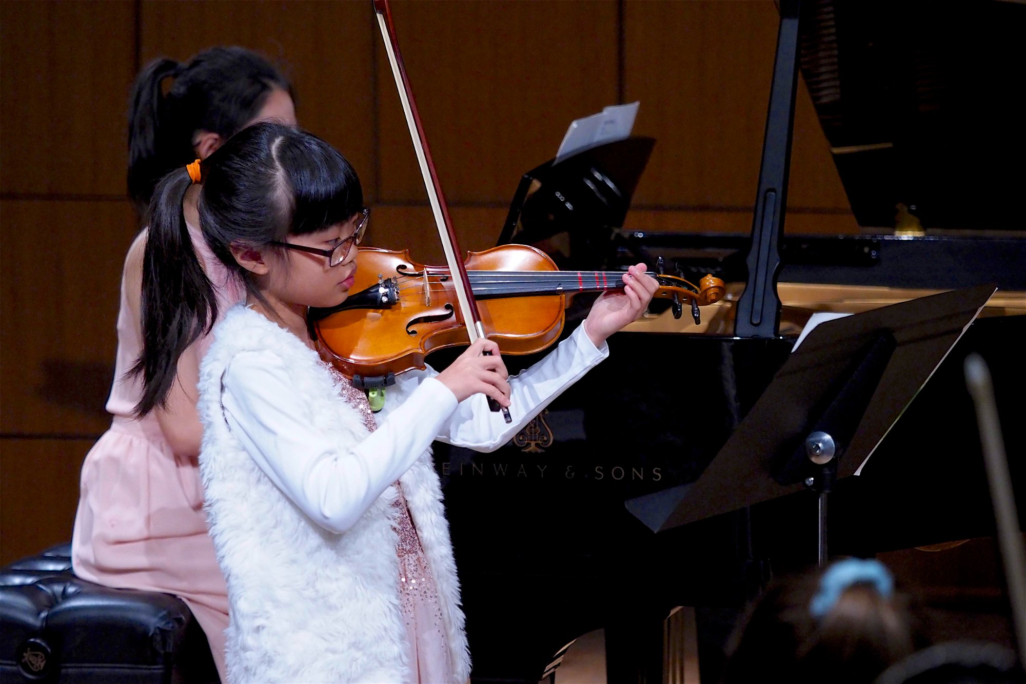 Student playing violin at recital with piano accompaniment