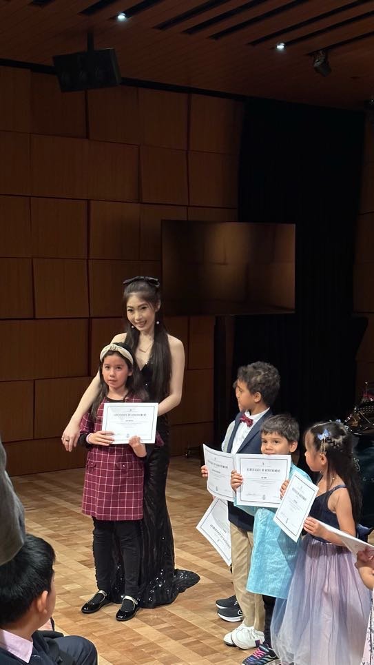 Cristina kneeling with student Brandon Li holding Steinway certificate and flowers at recital 2023