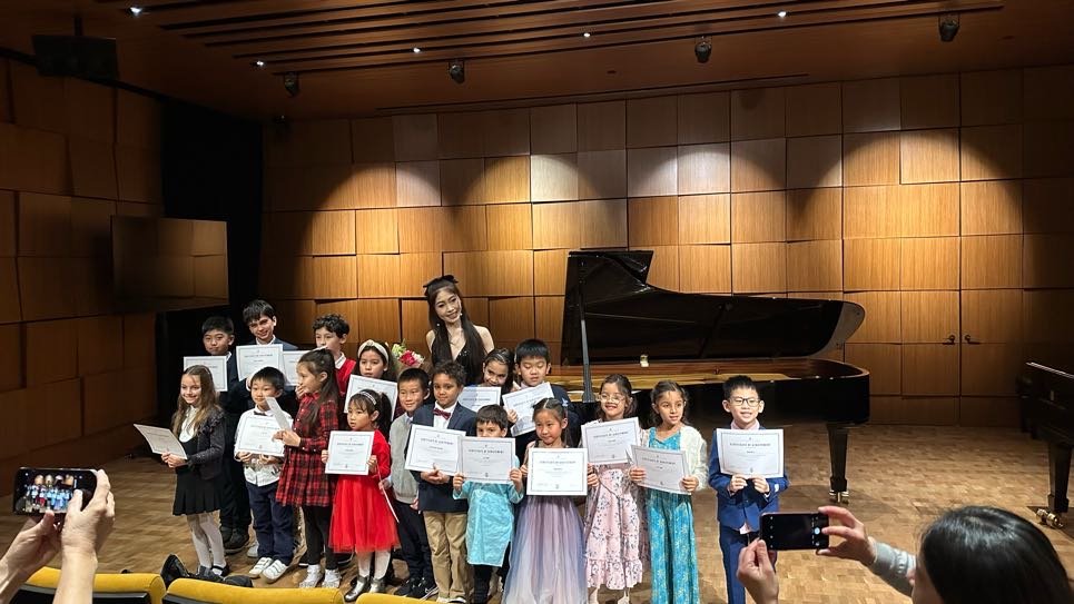 Cristina with student Brandon Li in front of Steinway grand piano at recital 2023
